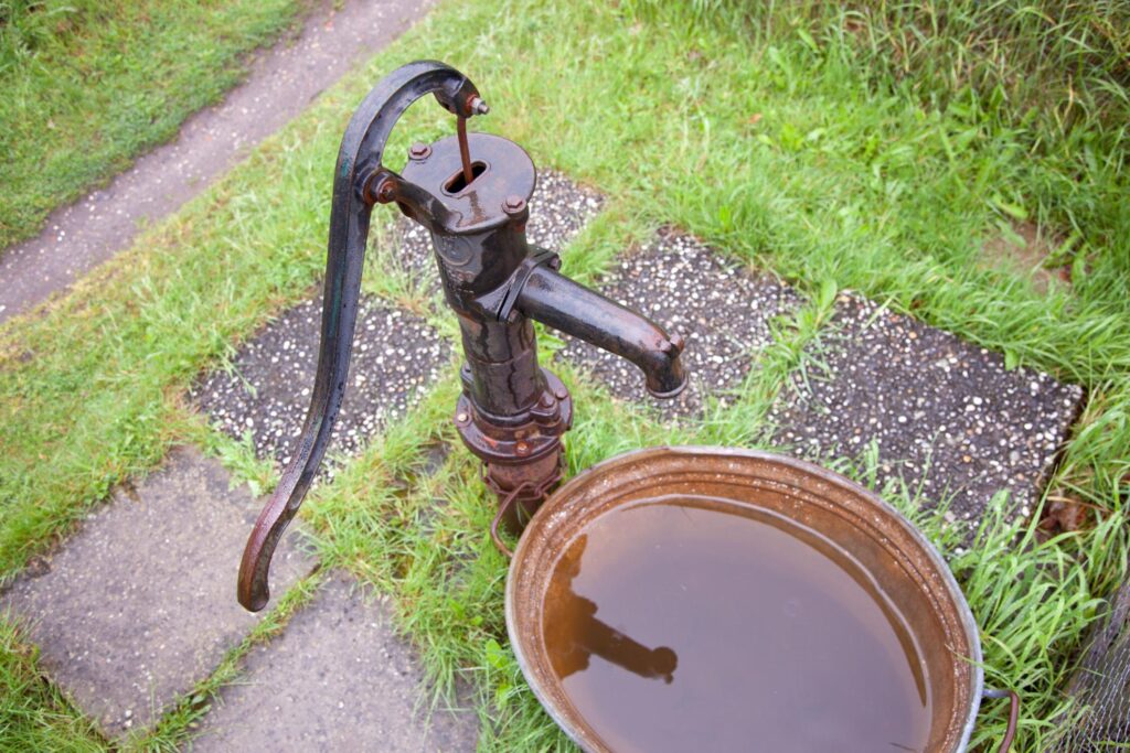 a rusty water faucet sitting on the side of a road
