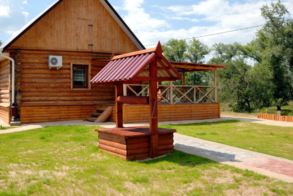 a wooden house with a red roof and a wooden bench in front of it